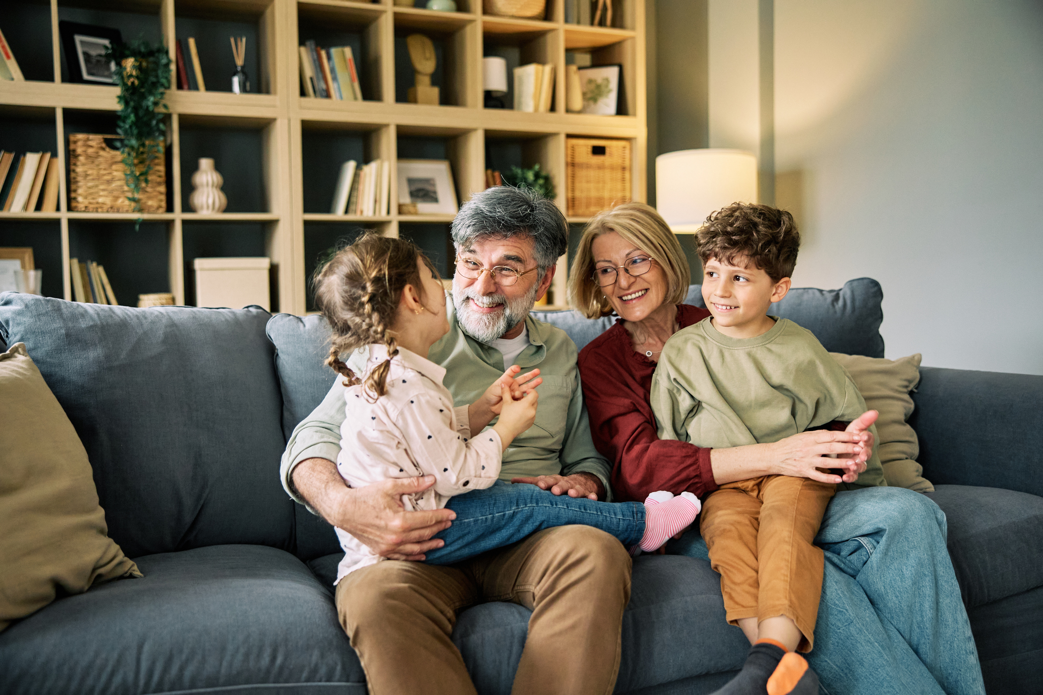 Grandparents laughing with their grandchildren on the couch at home